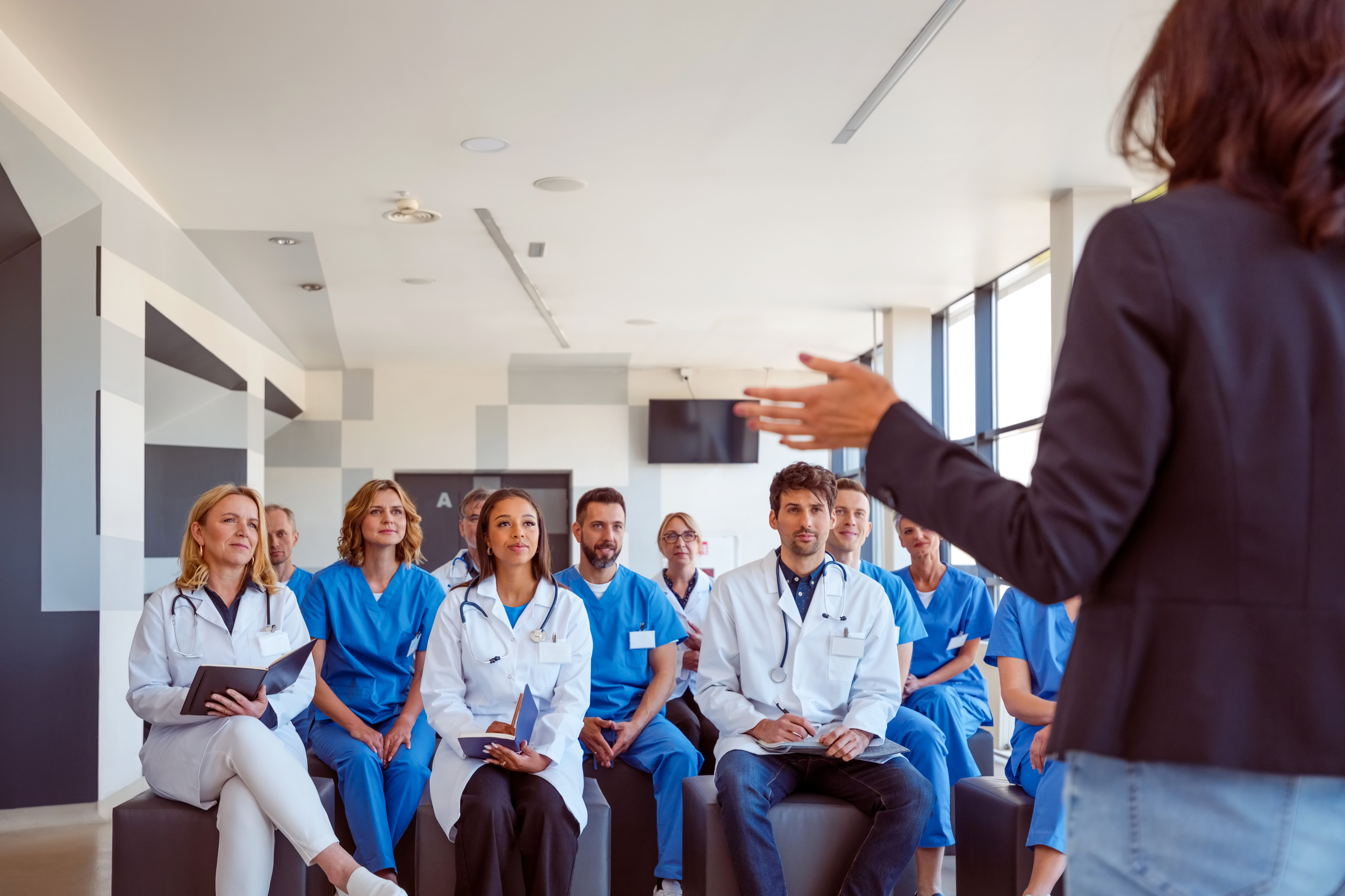 A woman talking in front of a group of doctors and nurses