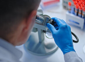 scientist looking at blood sample under microscope.