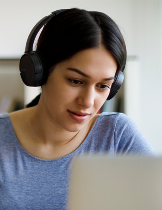 Woman wearing headphones while looking at a computer